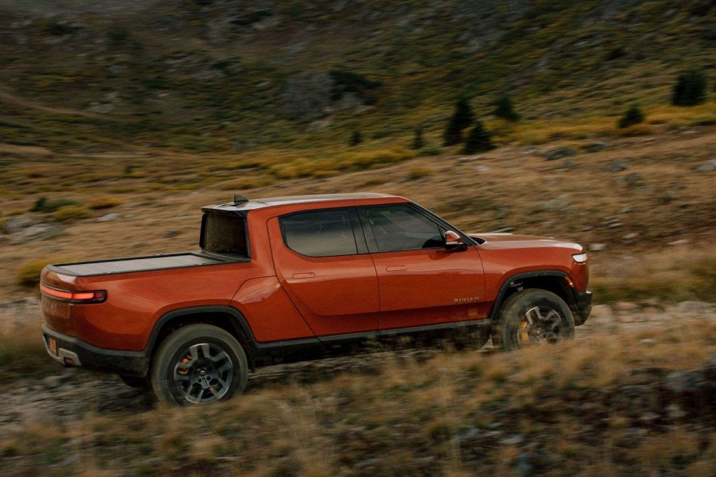 Red Canyon 2022 Rivian R1T electric pickup truck driving off-road on a rocky path