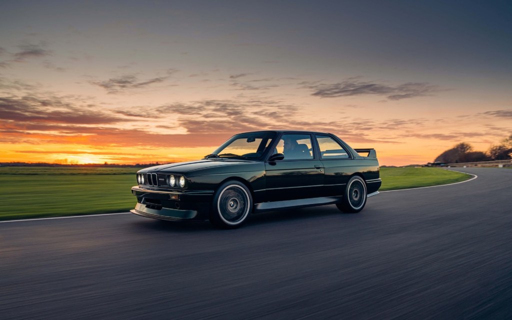 A black Redux Enhanced & Evolved BMW E30 M3 drives around a track