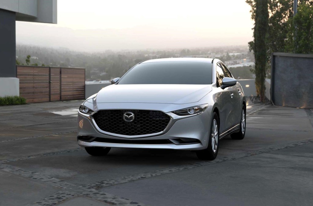 Silver 2022 Mazda3 Sedan parked near a large house