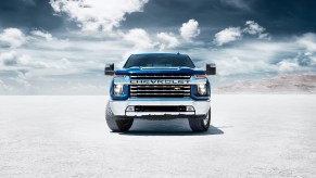 The front of a blue 2022 Chevy Silveado with clouds in the background