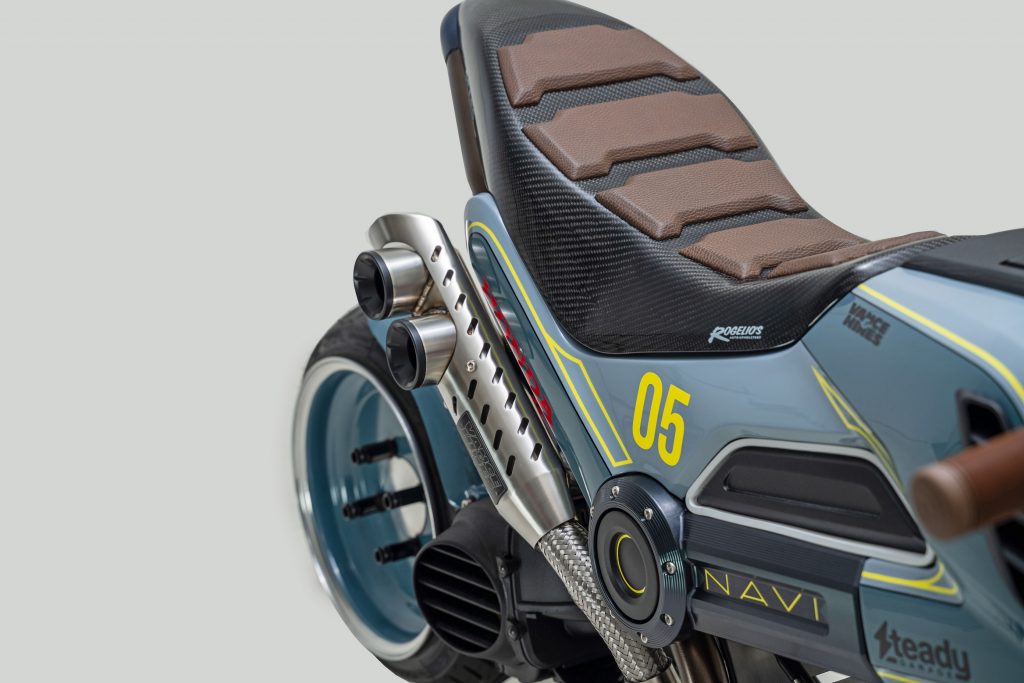 A close-up view of the blue-and-yellow Steady Garage 'Project Naviscape' custom 2022 Honda Navi's seat and exhaust