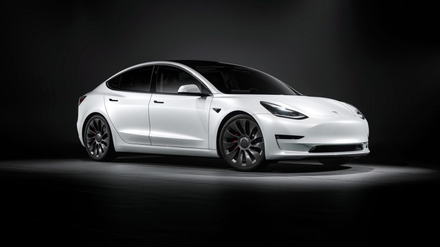 A white Tesla Model 3 EV sedan shot from the front 3/4