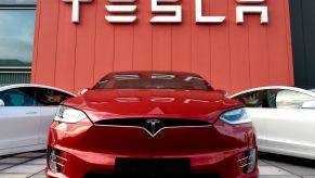 Red Tesla building with a red car and two white cars in front of it with Tesla written in white.