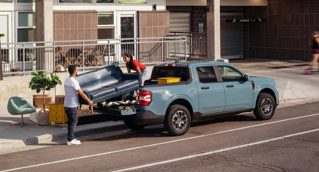 People are loading a sofa into a blue 2022 Ford Maverick's Flexbed. 