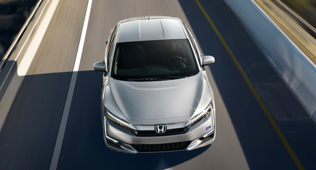 A silver Honda Clarity is driving on the road. 