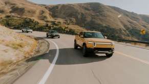 Three 2022 Rivian R1T electric pickup trucks driving on a mountain road