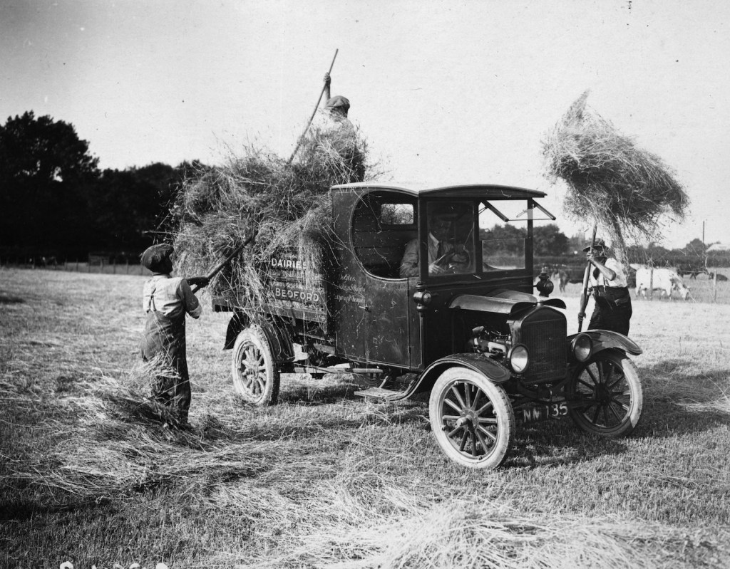 Pitching hay into a Ford Model T farm pickup truck. | Topical Press Agency/Getty Images
