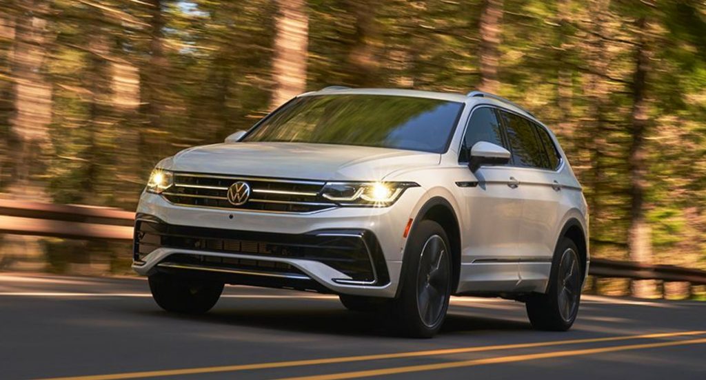 A white Volkswagen Tiguan is driving on the road. 