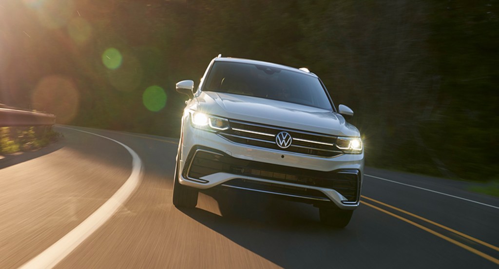 A white Volkswagen Tiguan is driving down the road.