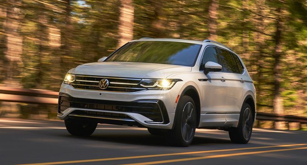 A white Volkswagen Tiguan is driving on the road.