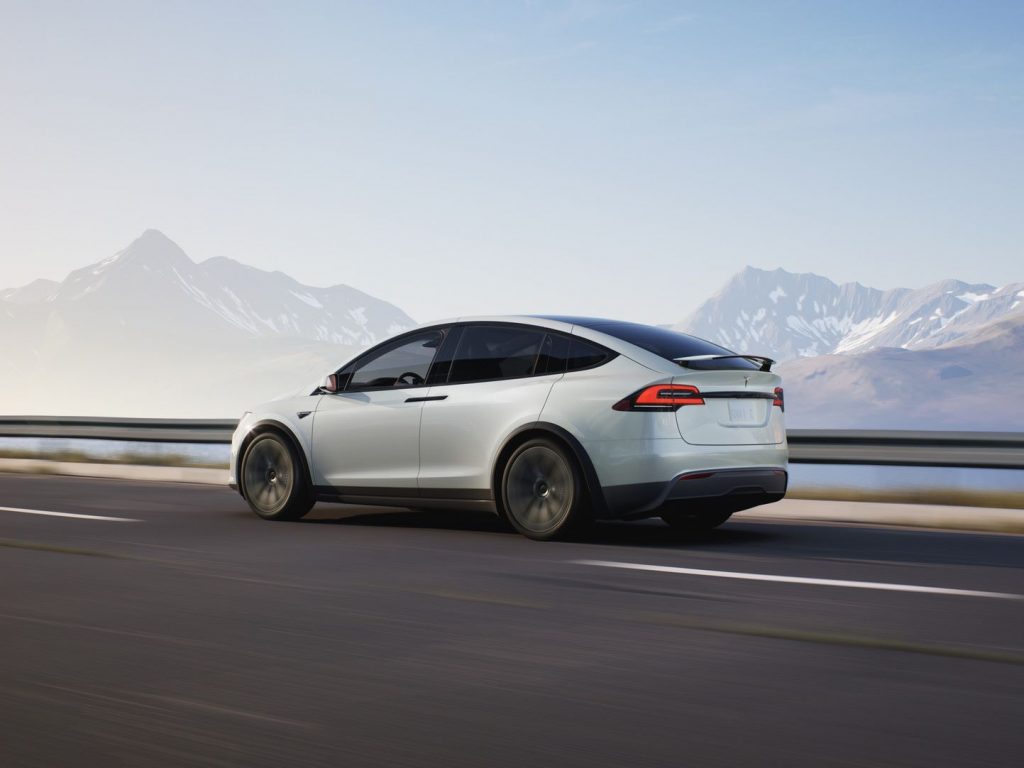 White 2022 Tesla Model X, an SUV with high gas mileage and fast acceleration, driving by mountains