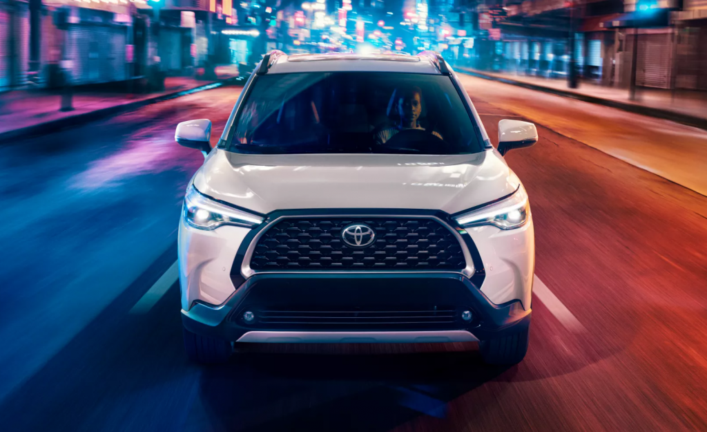 Wind Chill Pearl 2022 Toyota Corolla Cross driving on a city street at night