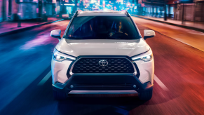 Wind Chill Pearl 2022 Toyota Corolla Cross driving on a city street at night