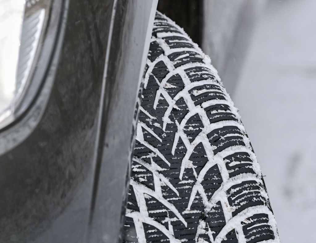Winter tires with snow in it on a black vehicle.