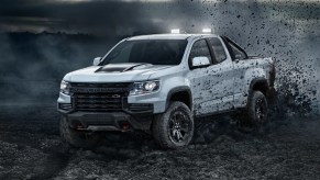 A white 2022 Chevy Coloardo off-roading in dirt and rocks.