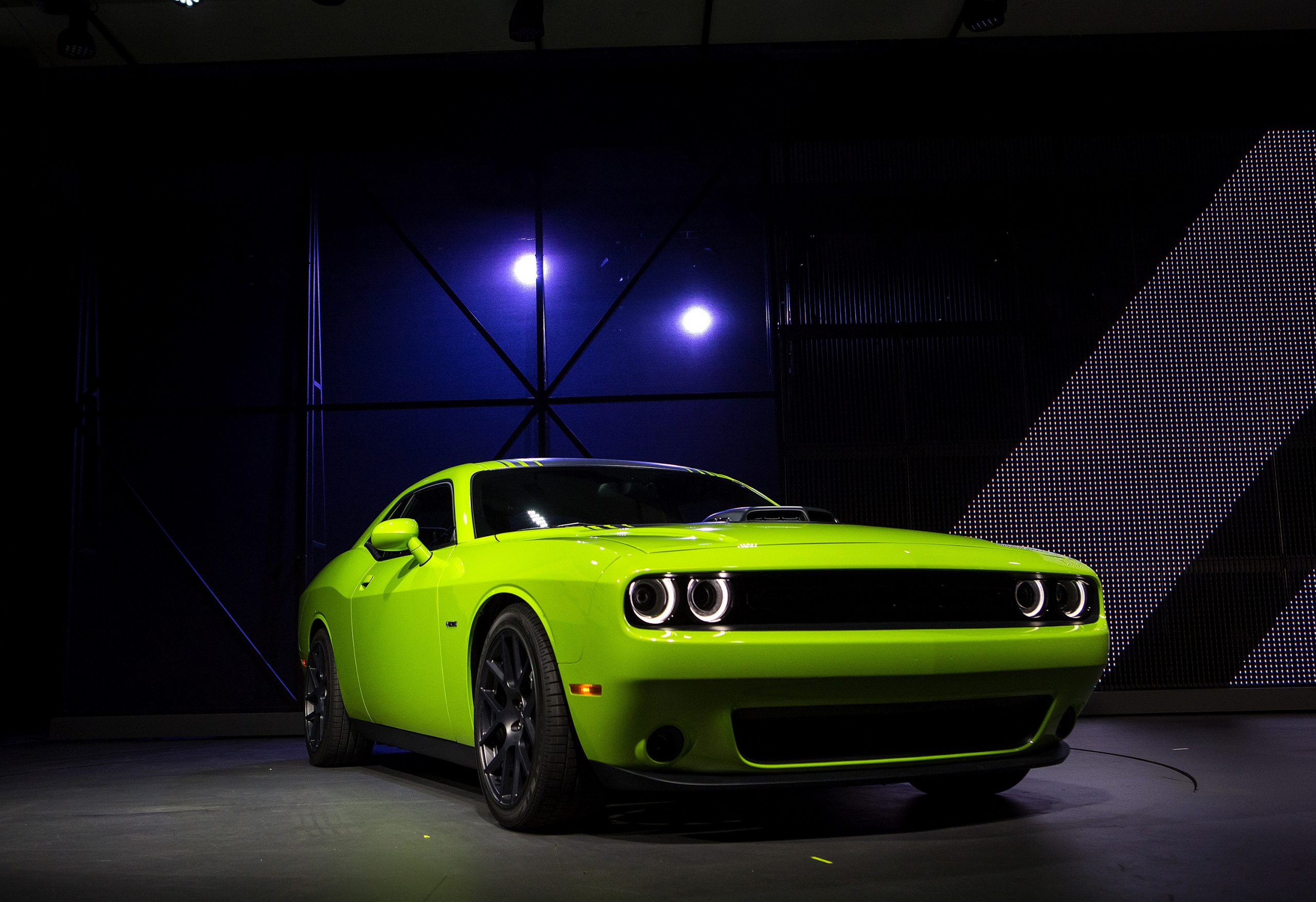 A lime green Challenger on a stage at an auto show, shot from the front 3/4