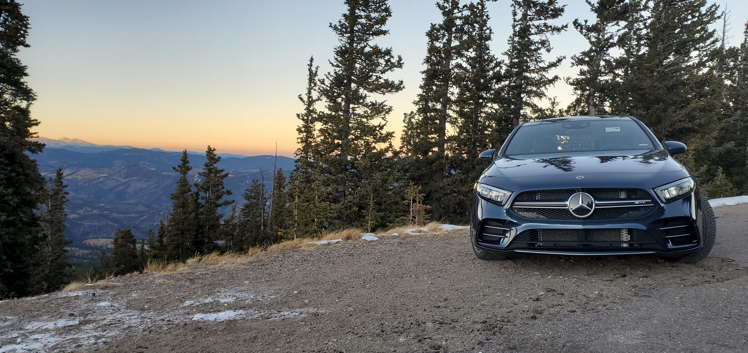 A blue AMG A35 sedan shot from the front on a mountain pass at sunset