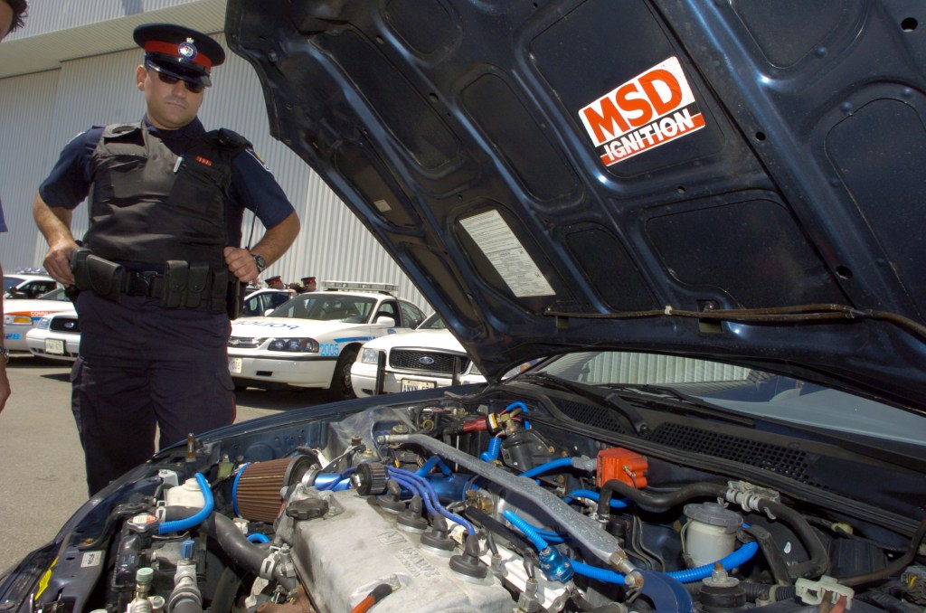 A police officer looks at the modified engine of a Honda Civic street racer seized by the police.