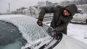 A man scraping ice off his windshield in Vladivostok, Russia