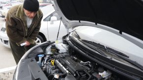 A man checks out the engine bay of a car