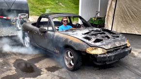 Alex Giroux sitting in his burnt-up Mazda Miata