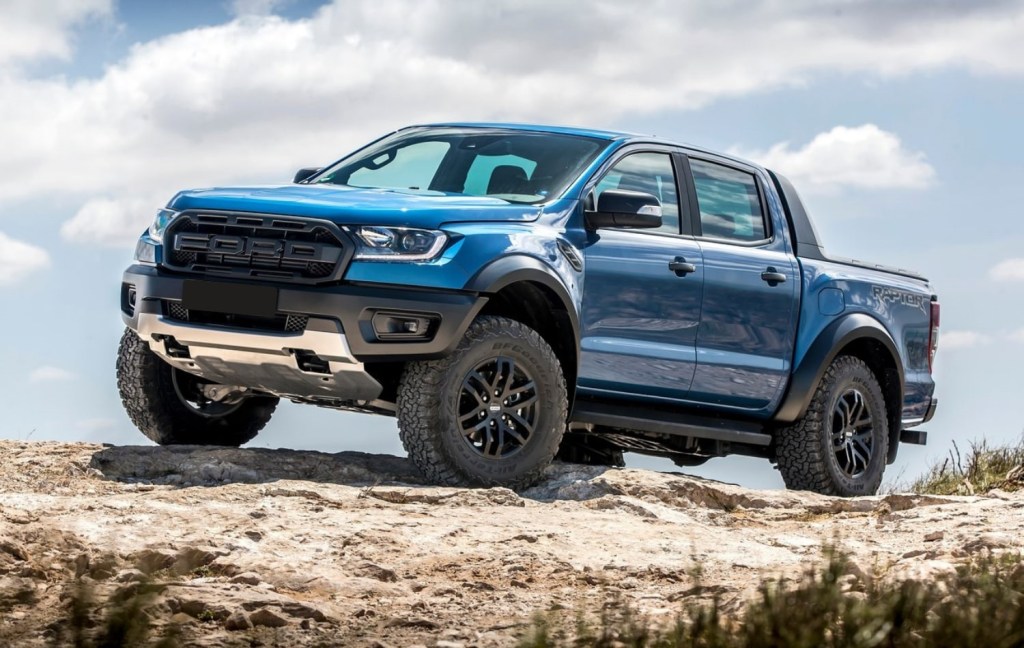 A blue 2021 Ford Ranger Raptor traversing a rocky terrain.