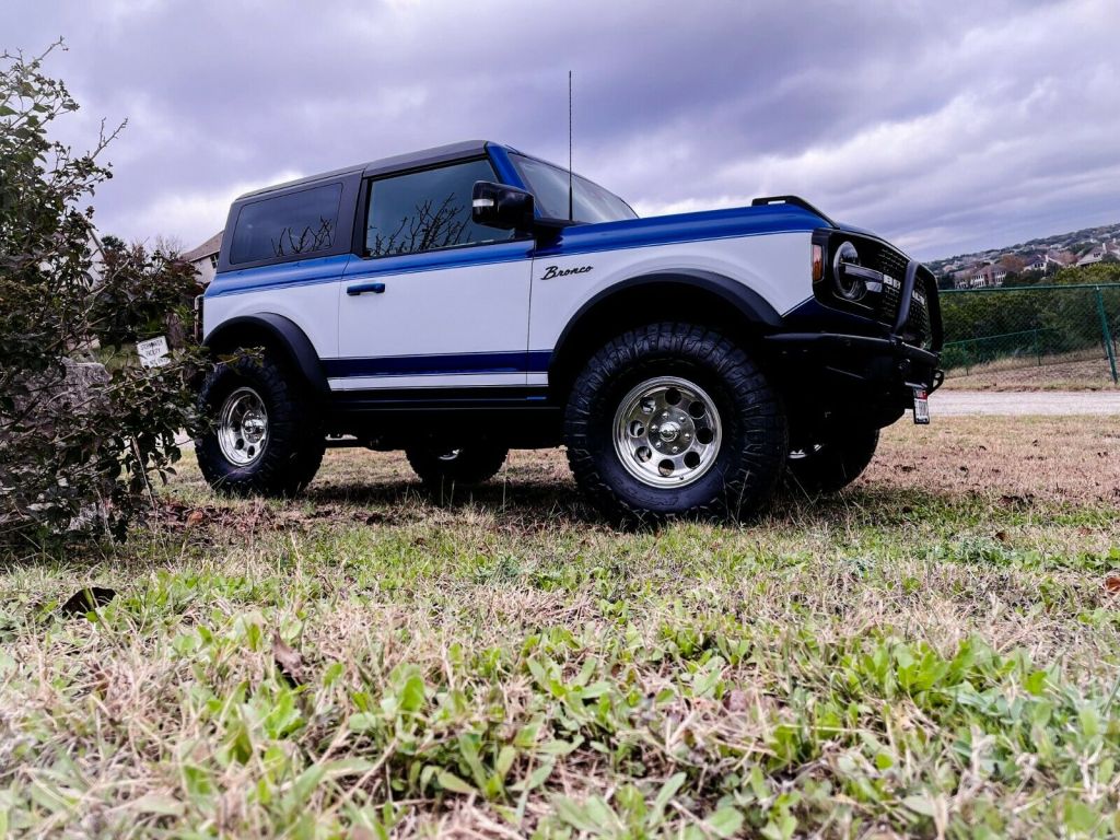 Blue and white retro ford bronco first editionparked on grass, it's for sale on ebay