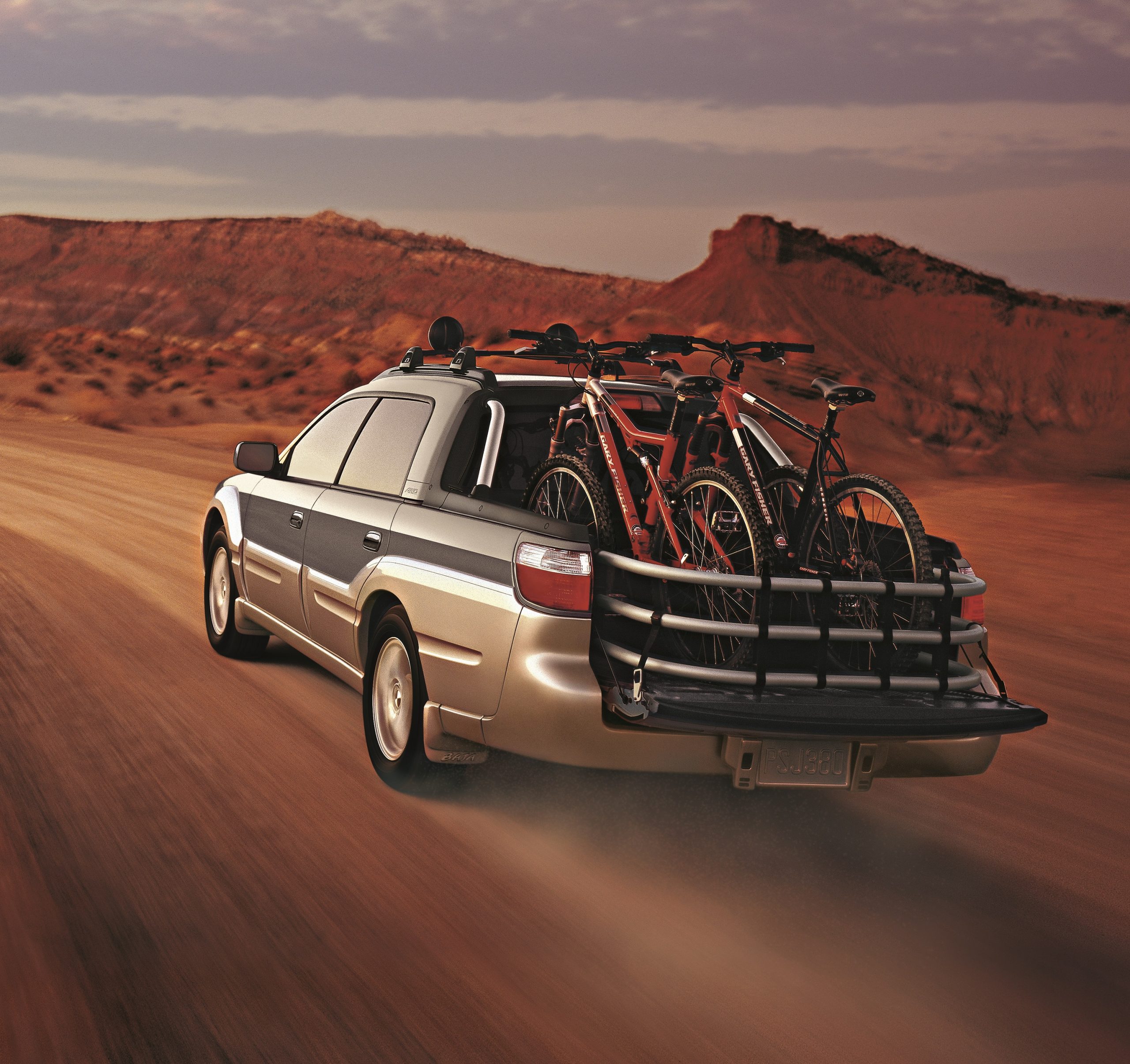 The rear of a Subaru Baja loaded with mountain bikes on a desert back road