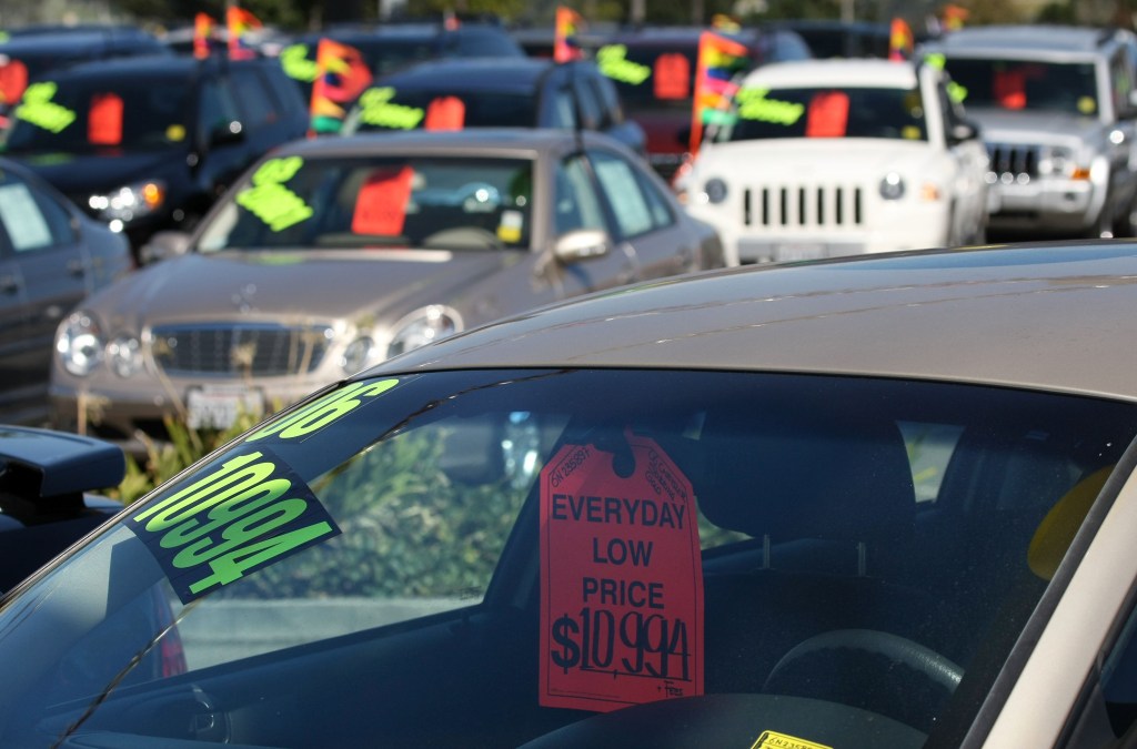  A price tag hangs from the rearview mirror of a car for sale at a Chrysler dealership in Colma, California