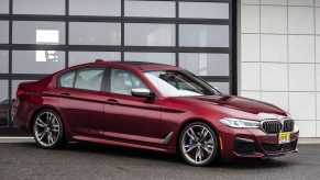 A 3/4 front view of a red BMW M550i xDrive parked in a driveway