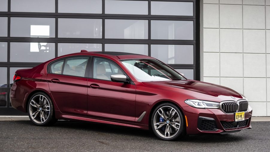 A 3/4 front view of a red BMW M550i xDrive parked in a driveway