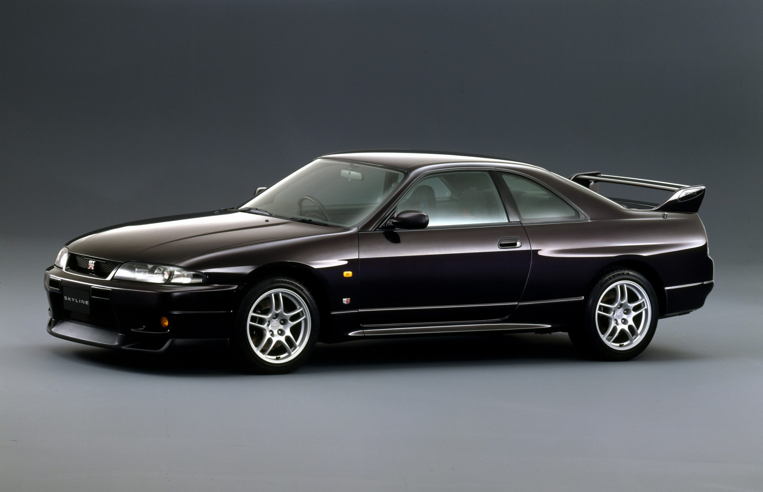 A black 1995 Nissan GT-R R33 shot from the front 3/4 in a photo studio