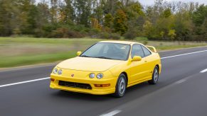 A yellow 2000 Acura Integra Type R drives down a road