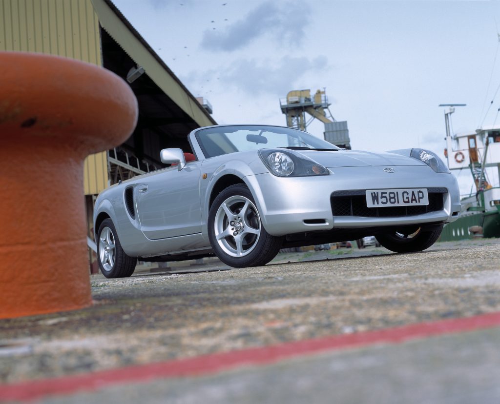 A silver 2000 Toyota MR2 Spyder convertible sports car on a dock