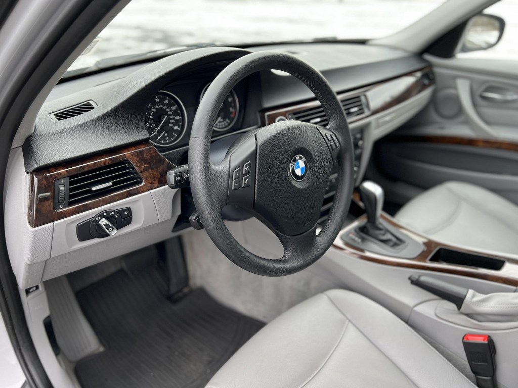 The gray-leather-upholstered front seats and wood-trimmed dashboard of a 2010 BMW 328i xDrive sedan