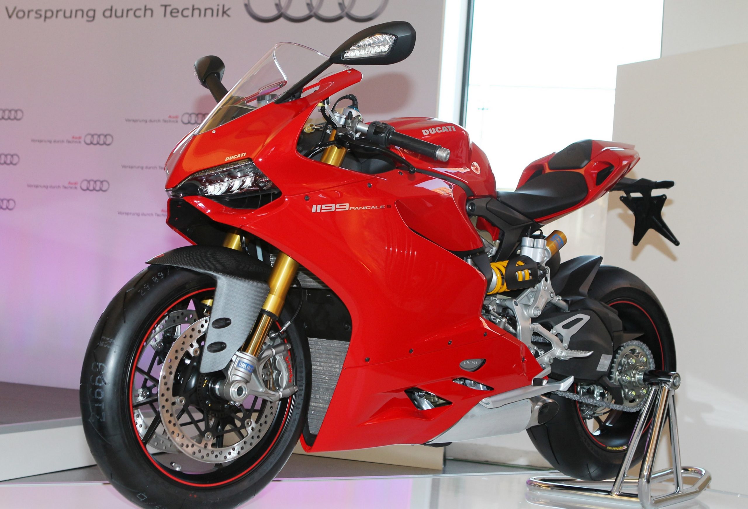 A red 2012 Ducati 1199 Panigale S on a rear-wheel stand on a stage