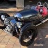 A black 2012 Morgan 3-Wheeler with a quiled-red-leather cabin