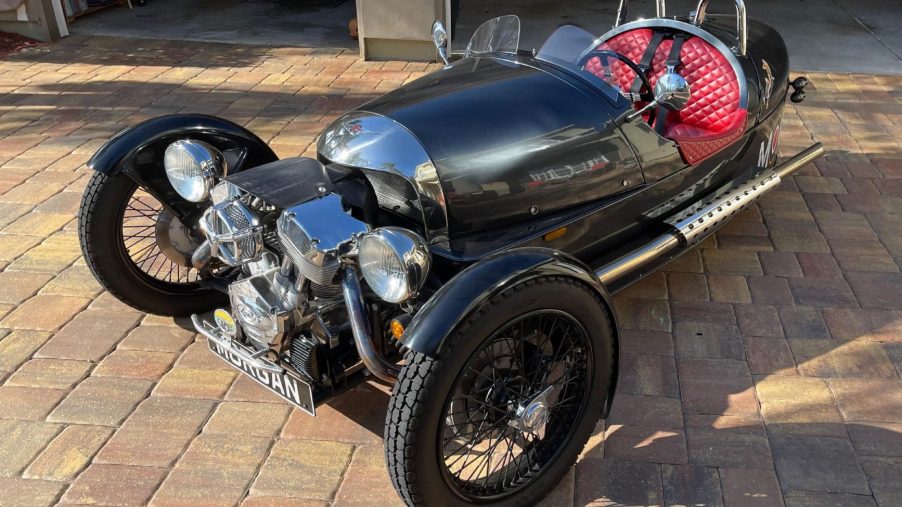 A black 2012 Morgan 3-Wheeler with a quiled-red-leather cabin