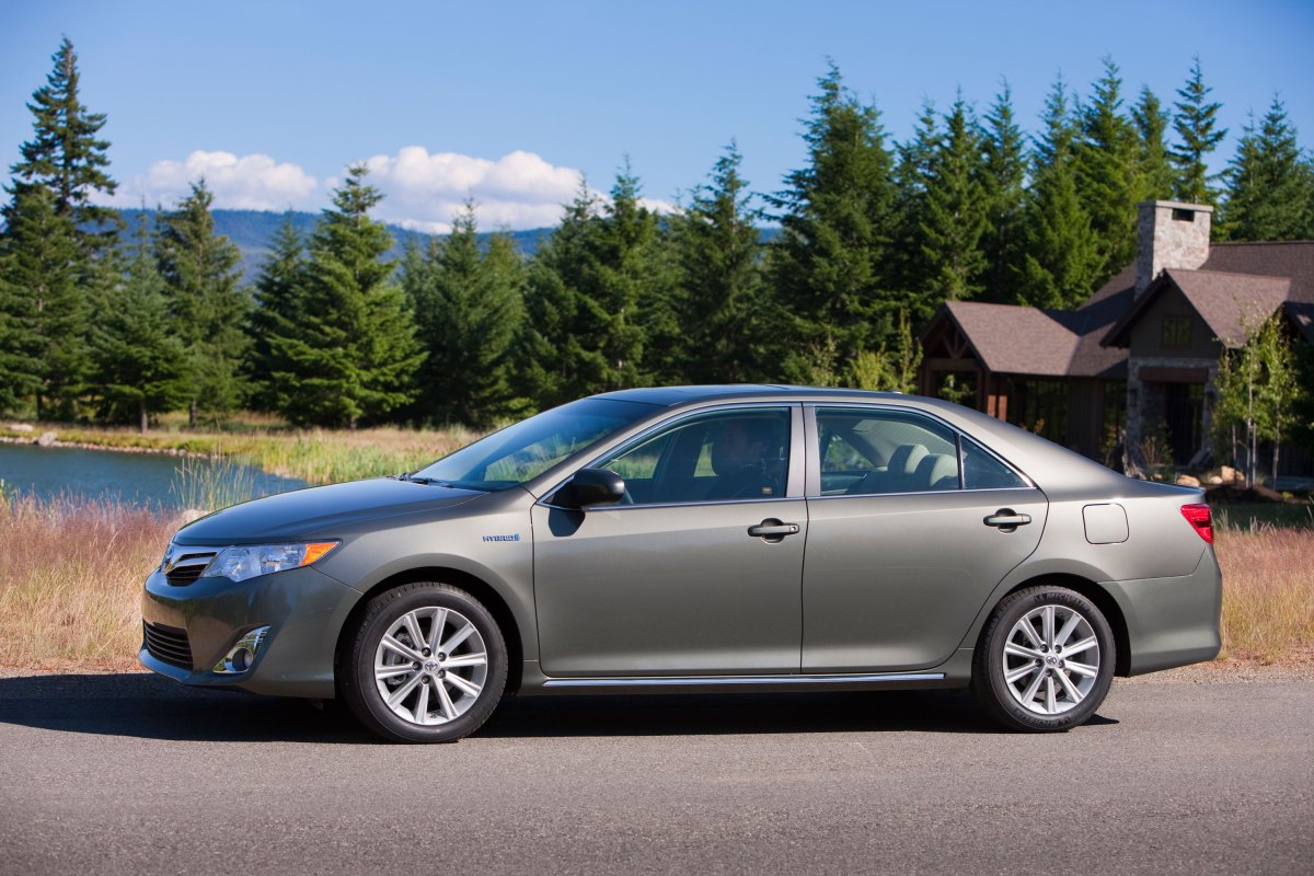A profile view of the 2012 Toyota Camry Hybrid in front of a house.