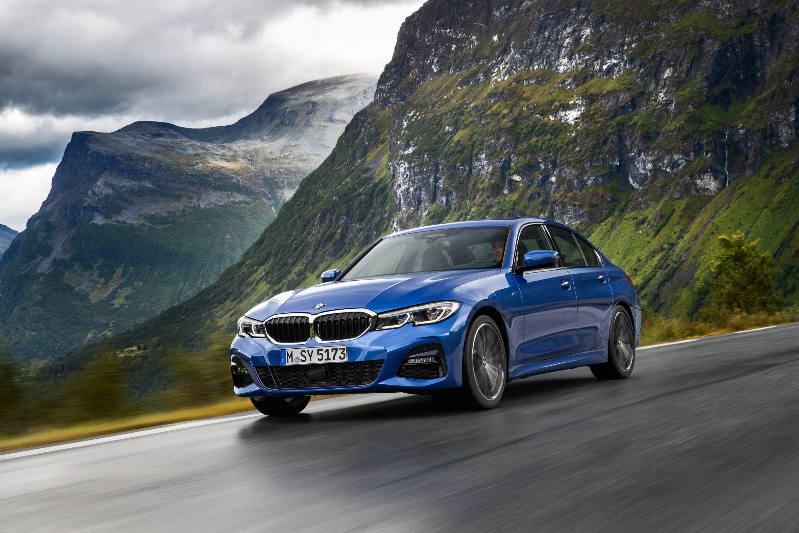 A blue 2019 BMW 3 Series shot from the front 3/4 on a cliffside