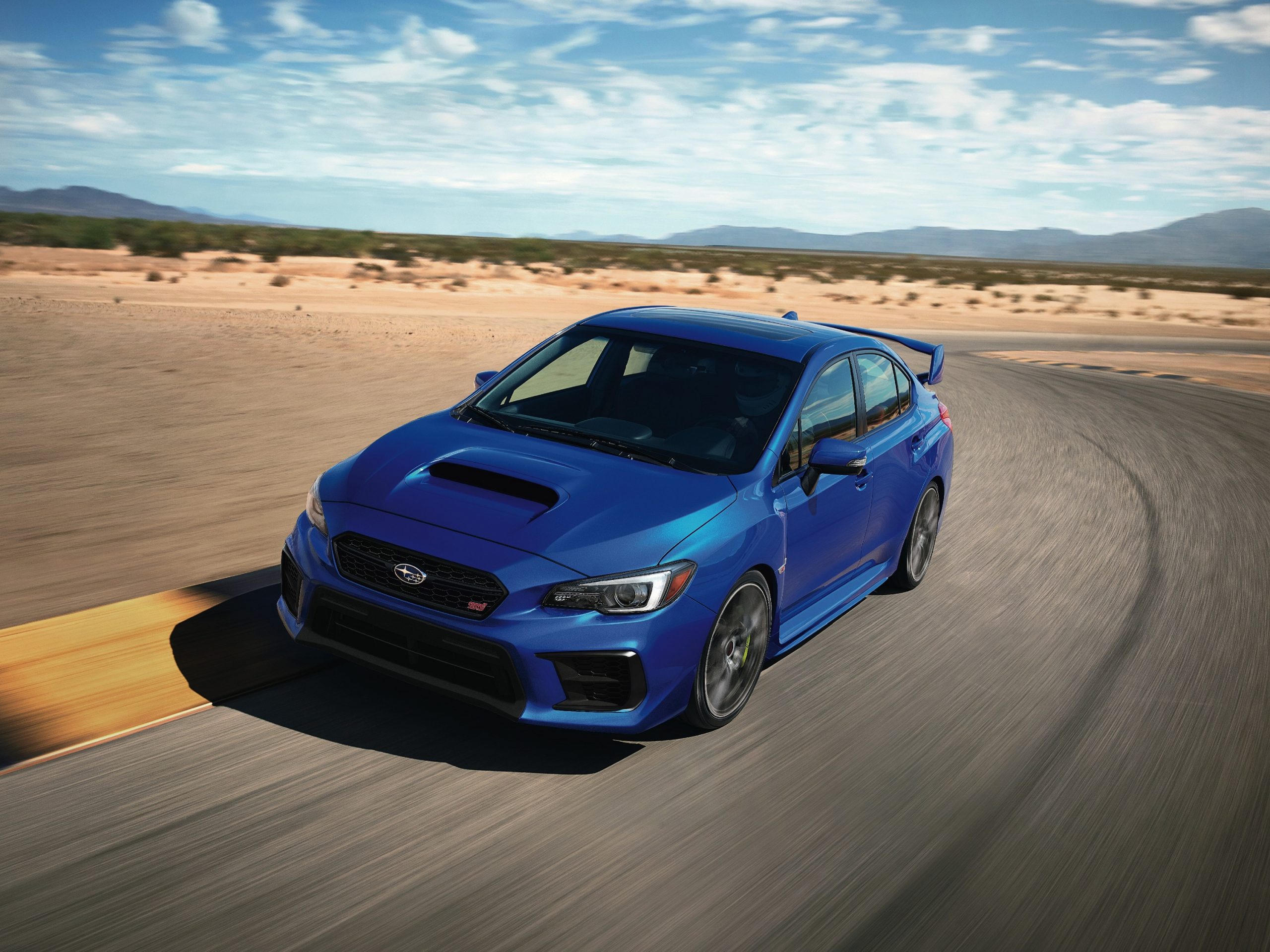 A Rally Blue Subaru WRX STI shot from the front 3/4 at Willow Springs