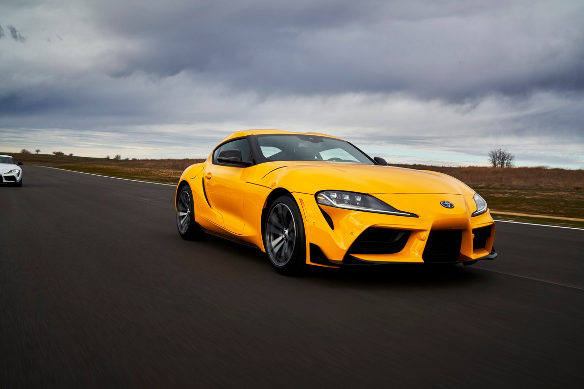 A yellow 2021 Toyota Supra 2.0 drives on a race track being followed by a white Supra