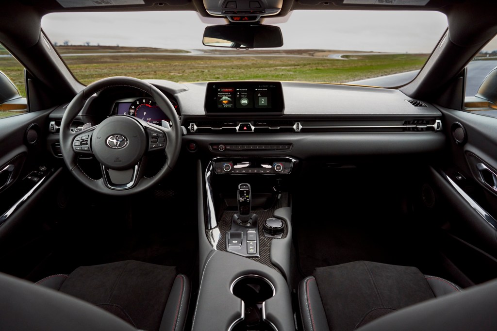 An interior view of a 2021 Toyota Supra showing the steering wheel, dashboard and infotainment system
