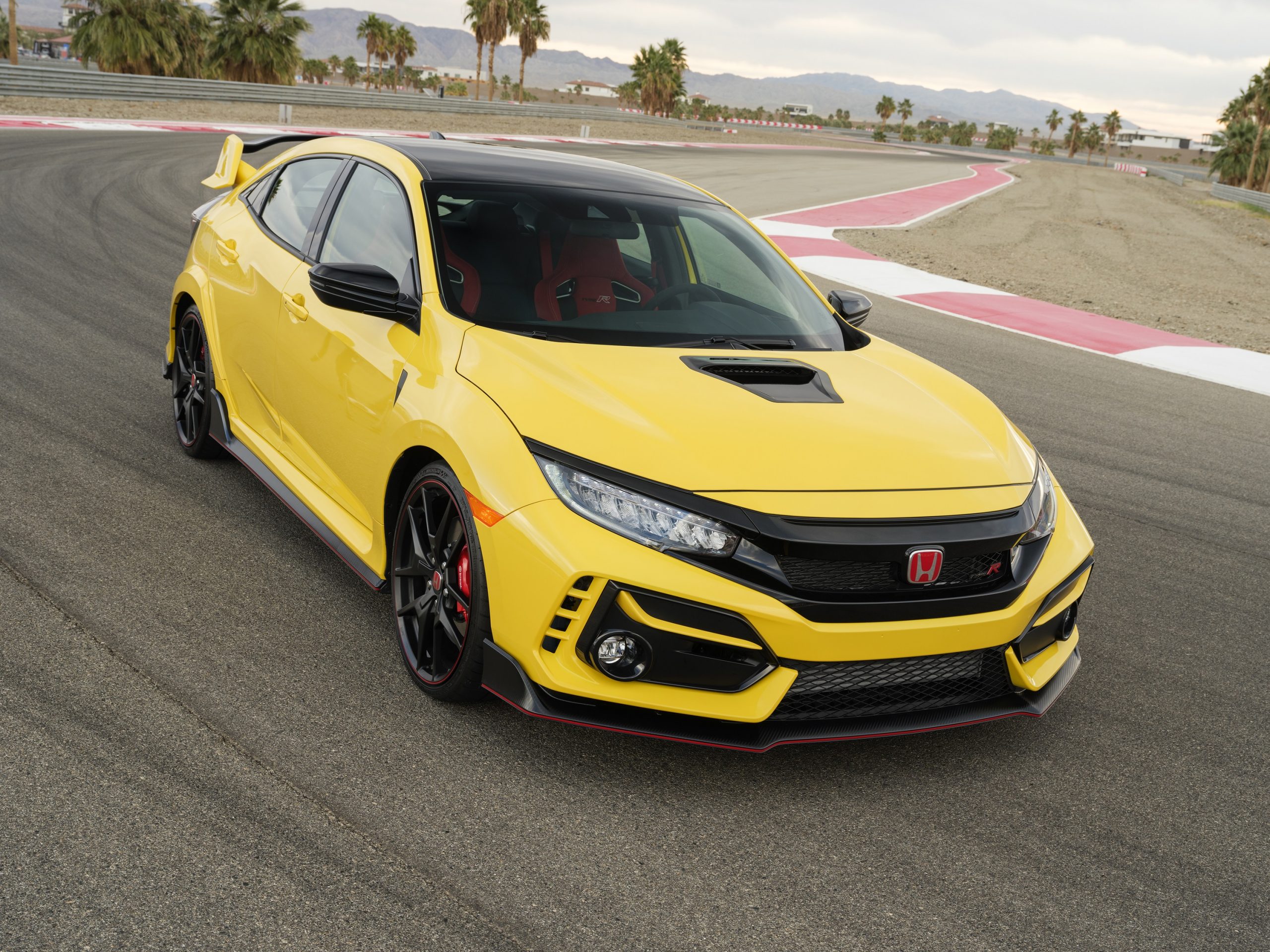 A yellow Honda Civic Type R with one of the worst car trends: fake vents, photographed on a race track
