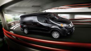A promotional shot of a 2021 Nissan NV200 light commercial van driving through a parking garage
