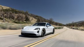 A white 2021 Porsche Taycan drives down a desert road