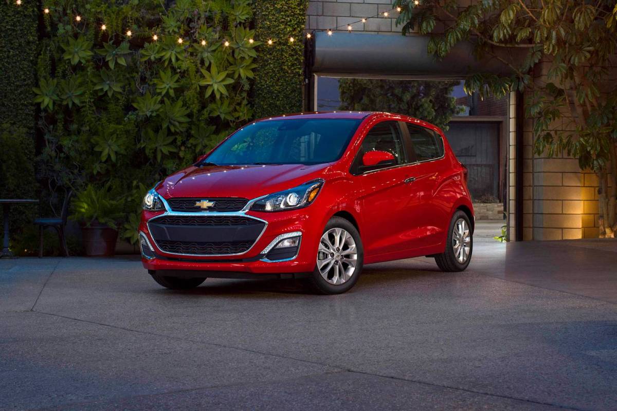 A 3/4 front view of a red 2021 Chevrolet Spark parked in a driveway.