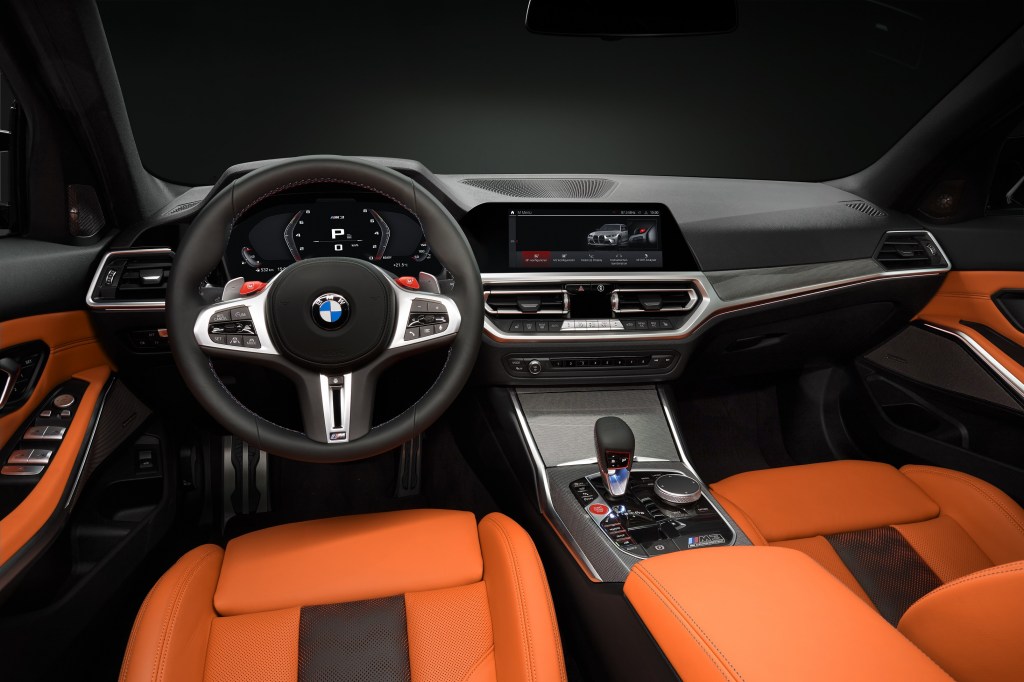 The orange-leather-upholstered front seats and silver dashboard of a 2022 BMW M3 Competition xDrive