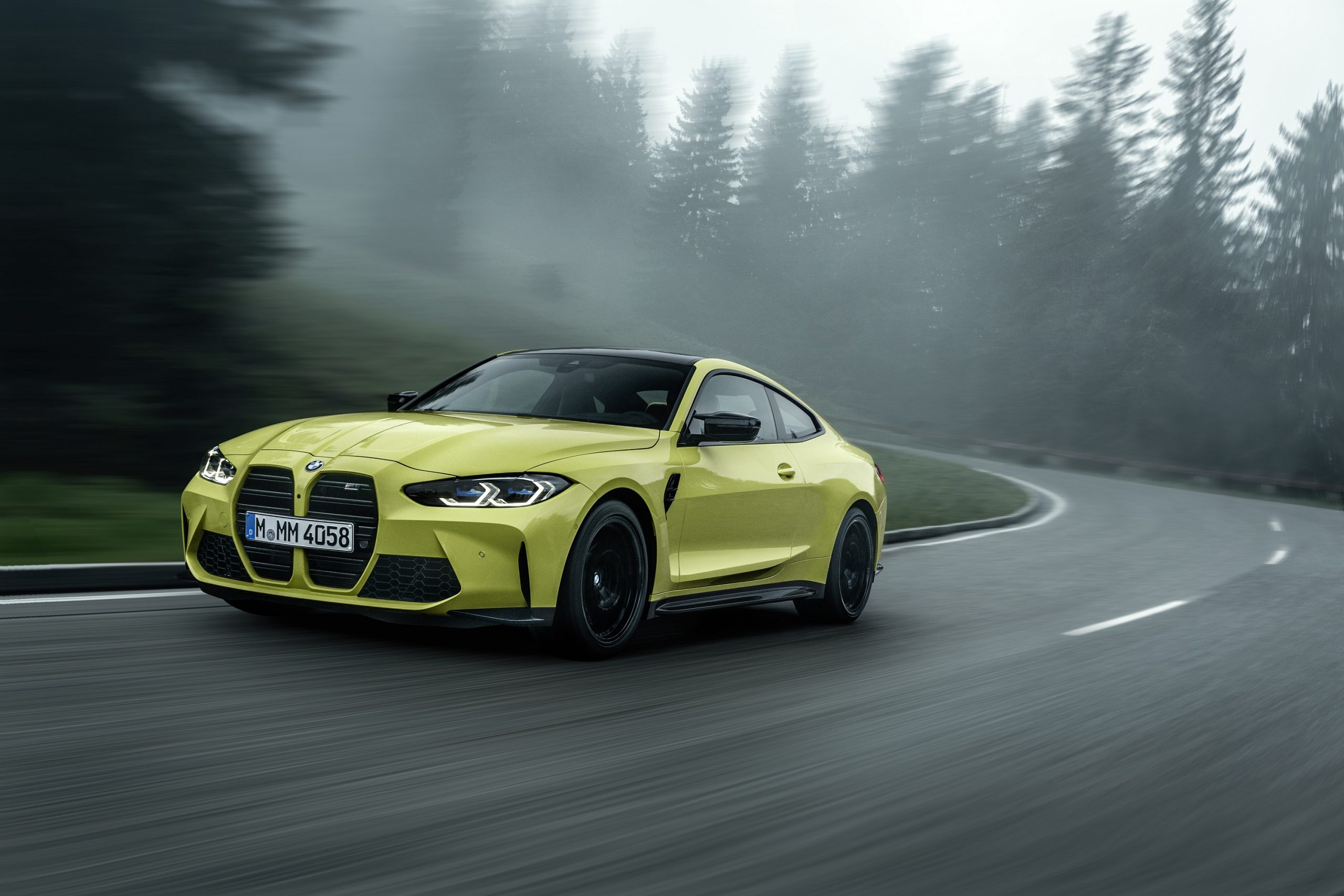 A yellow 2022 BMW M4 shot on a rainy day in the German woods