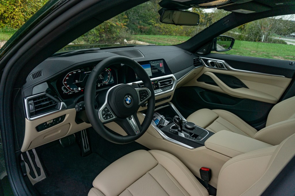 The tan-leatherette front seats and black dashboard of a 2022 BMW M440i xDrive Gran Coupe